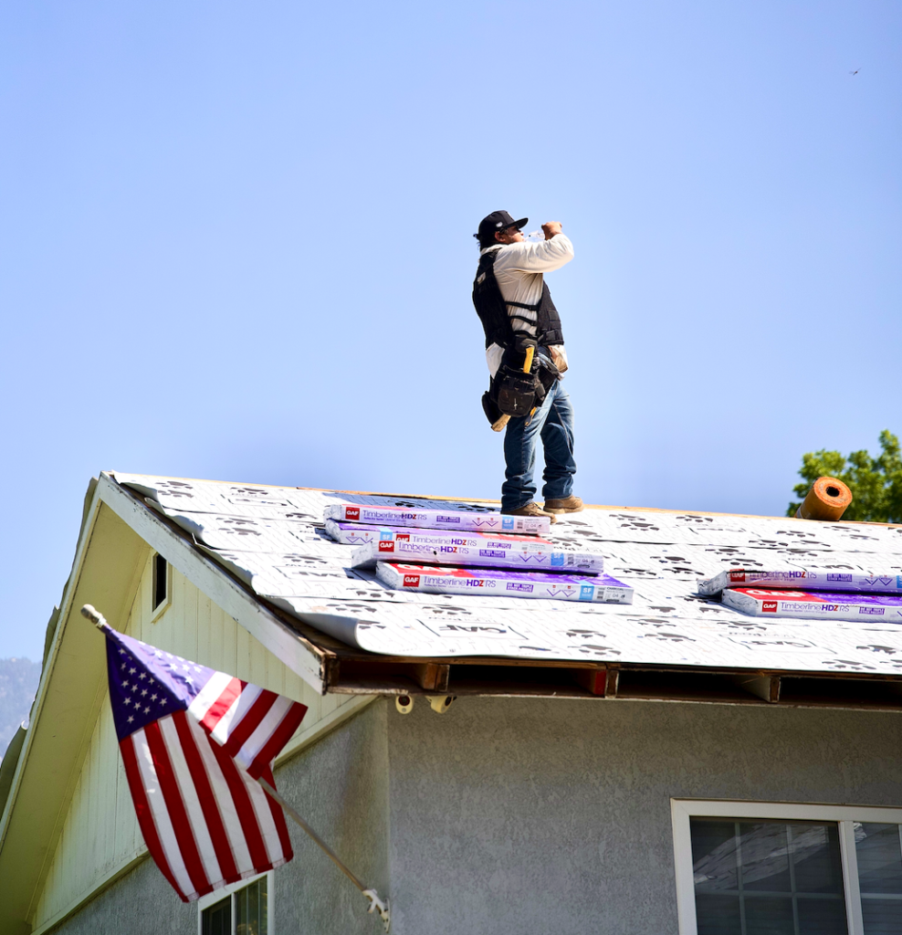 Green Ladder roofer on a GAF Timberline HDZ reroof with American flag