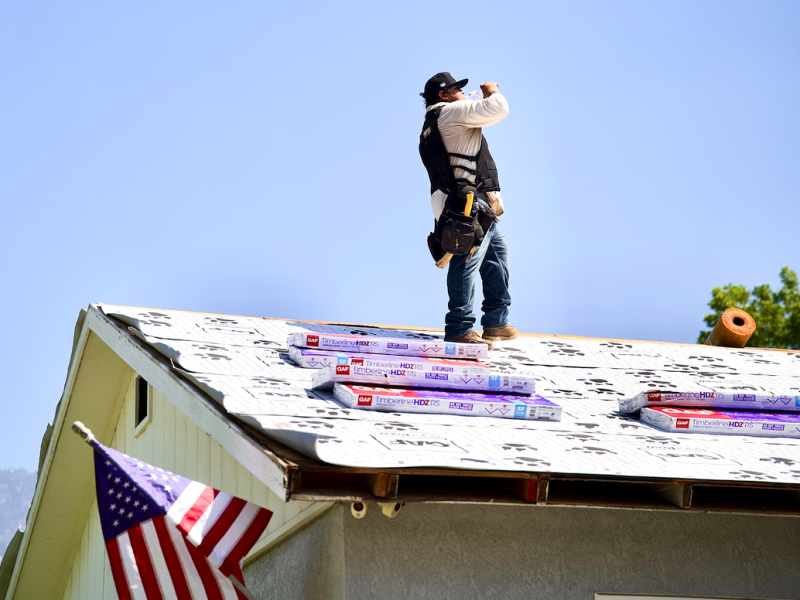 Green Ladder roofer on a GAF Timberline HDZ reroof with American flag