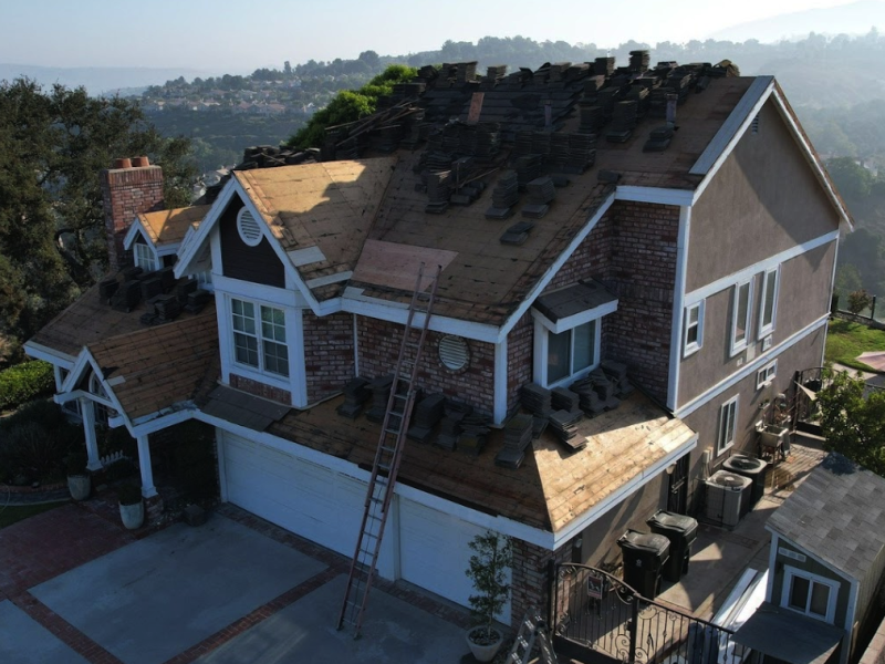 Green Ladder branded drone shot of a hillside home tear-off and reroof